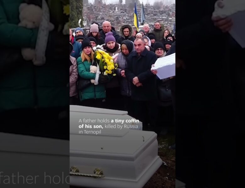 A father gently rocks the small coffin of his one-year-old son.
