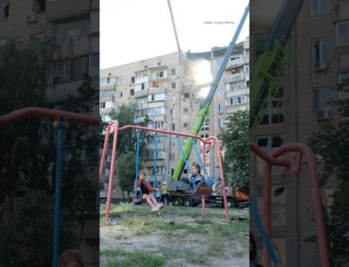 Children swing on a playground beside a building struck by a Russian attack in Kyiv on July 6