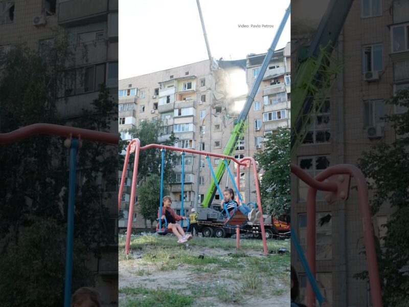 Children swing on a playground beside a building struck by a Russian attack in Kyiv on July 6